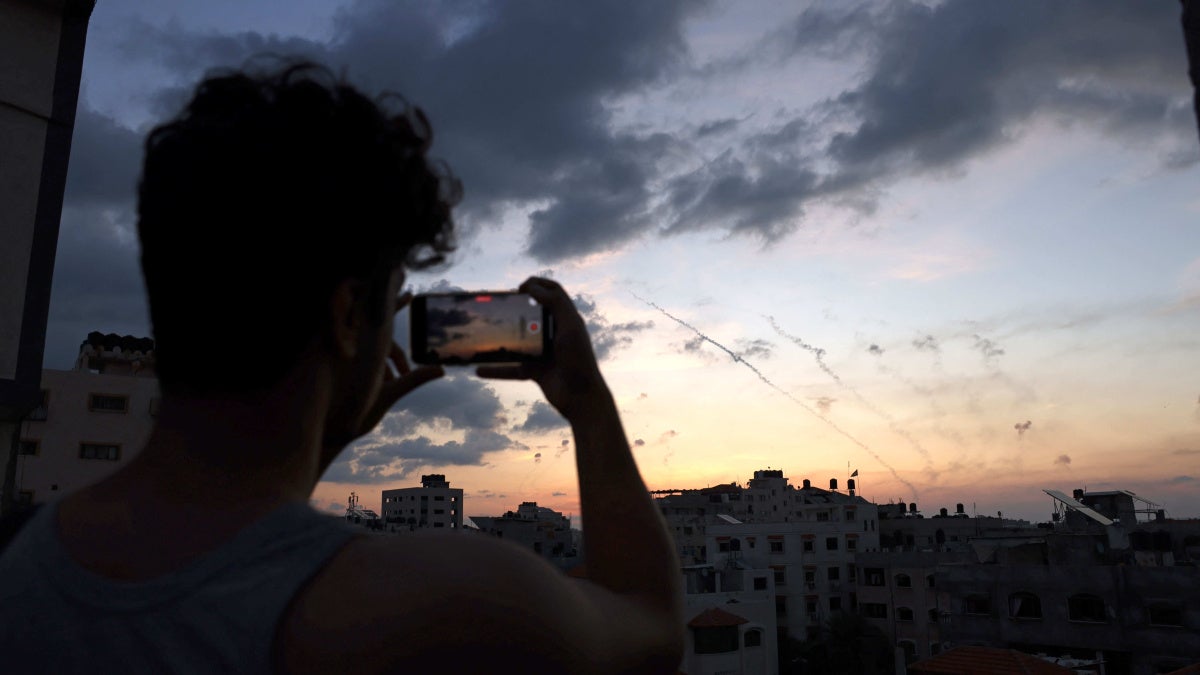 A man records a video with his mobile phone of rockets being fired
