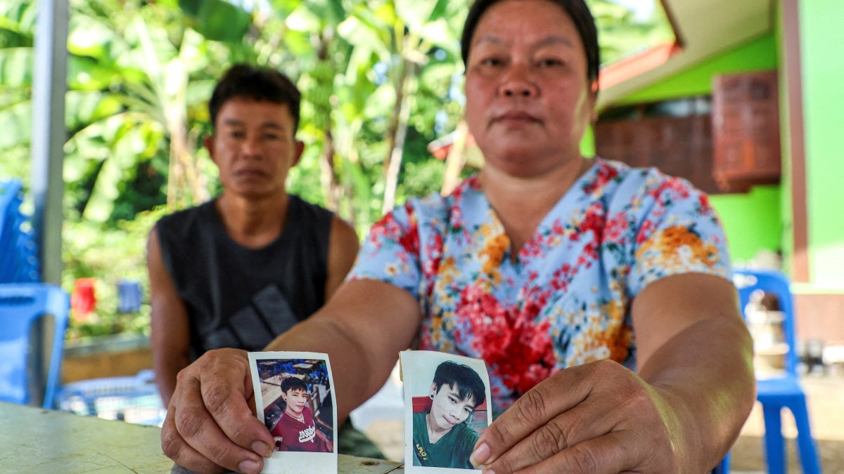 Thawatchai and Thongkoon On-kaew, parents of Natthaporn, hold photos of him outside their home in Nakhon Phanom, Thailand, October 10, 2023. Natthaporn was working in Israel when members of Palestinian armed groups took him hostage on October 7, 2023.