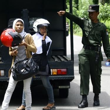 A sharia police officer escorts women caught wearing tight pants during a street raid in Arongan Lambalek district in Indonesia's Aceh province on May 26, 2010.