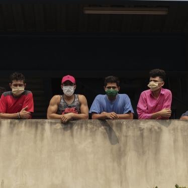 In this May 4, 2020 photo, men wearing protective face masks look out from a building where they are being held for violating a quarantine decreed by the government as part of measures to curb the spread of COVID-19, in San Salvador, El Salvador. 