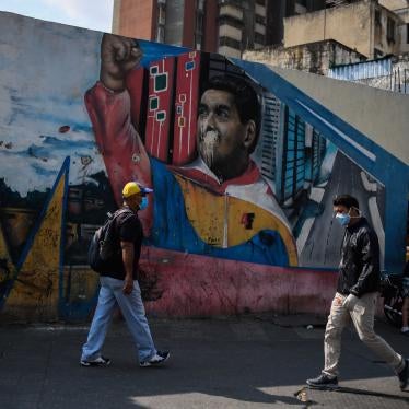 People wearing face masks walk past a mural depicting Venezuelan president Nicolas Maduro in Caracas on April 17, 2020, amid the novel coronavirus (COVID-19) outbreak. 