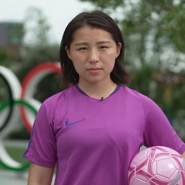 Soccer player holding ball in front of Olympic rings