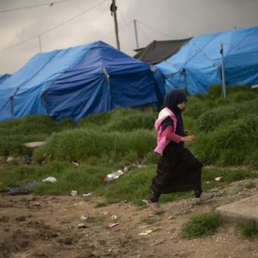 A girl walks through a tented area at Roj camp.