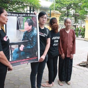 The family of Trinh Xuan Tung (his mother Nguyen Thi Cuc, his wife Nguyen Thi Mien, and his two daughters Trinh Kim Tien and Trinh Cam Tu) outside the court on July 17, 2012, waiting to attend appellate proceedings in the trial of former Col. Nguyen Van Ninh, convicted of causing Trinh Xuan Tung’s death. The poster features a picture of the perpetrator and slogans calling on authorities to impose a longer prison term. © 2012 Dan Lam Bao & contributors.