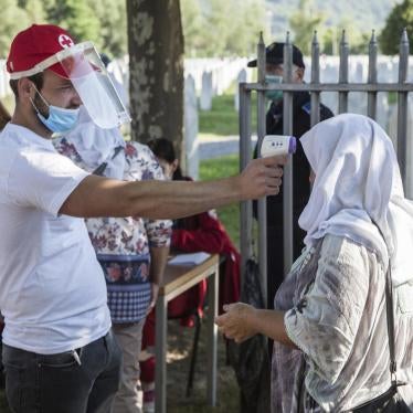 A health worker measures a visitor’s temperature before granting access to the Potocari memorial, illustrating the impact of the coronavirus pandemic on this year's commemoration of the twenty-fifth anniversary of the Srebrenica genocide. 