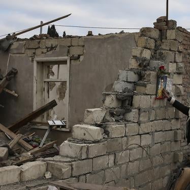 A woman touches a photograph of a child at the ruins of his house. 