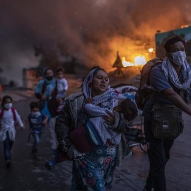 Refugees and migrants carrying their belongings flee a fire burning at the Moria camp on Lesbos island, Greece, Wednesday, Sept. 9, 2020. Successive fires that started before dawn on September 9 devastated the site and rendered 12,000 inhabitants homeless. 
