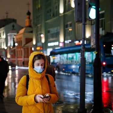 A woman wearing a face mask looks at her smartphone as she walks through a street in Moscow, Russia, November 23, 2020. 