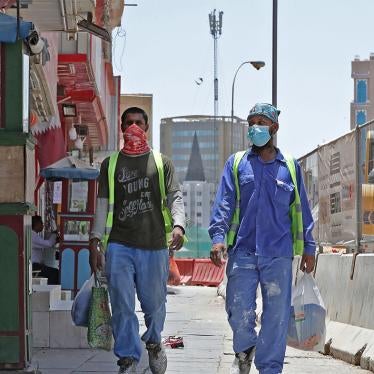 Workers wearing protective masks walk by on a street in Qatar's capital Doha, on May 17, 2020.