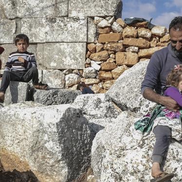 A man sits with his children at the remains of an ancient church in the village of Babisqa, Syria.