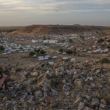 A Tigrayan girl sits atop a hill overlooking the Um Raquba refugee camp