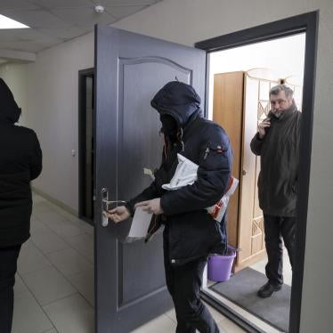 Police in Minsk carry documents and computers out of the office of the Belarusian Association of Journalists on February 16, 2021, as Andrei Bastunets, the head of the organization, looks on.