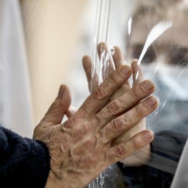 Relatives touch each other's hand through a plastic film screen and a glass to avoid contracting Covid-19 at the San Raffaele center in Rome, Italy, Dec. 22, 2020