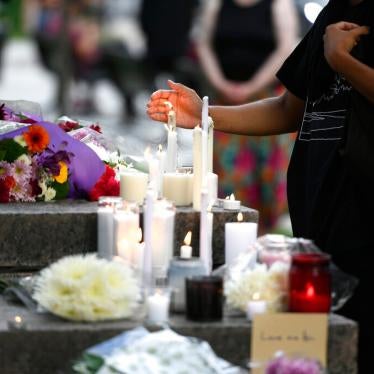 A mourner shields a candle from the wind after placing it at a memorial for the four family members who were killed in a vehicle attack in London, Ontario, in Ottawa, on Tuesday, June 8, 2021.