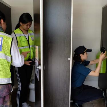 Three women investigate a bathroom stall