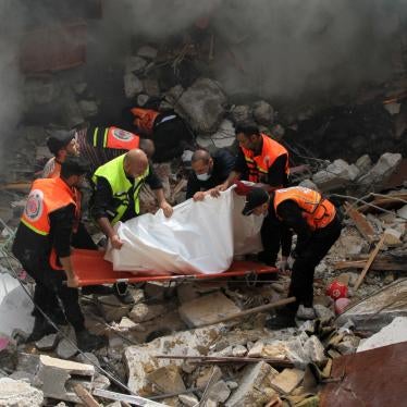 Members of the Palestinian civil defense remove the body of one of the 44 civilians killed after three multi-story residential buildings collapsed as a result of Israeli airstrikes in central Gaza City