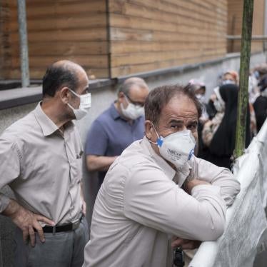 An Iranian man wearing a protective face mask looks on as people line-up to receive China's Sinopharm vaccine in central Tehran on July 19, 2021. 