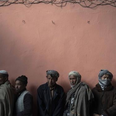 Men wait in a line to receive cash at a money distribution organized by the World Food Program in Kabul, Afghanistan, November 3, 2021. 
