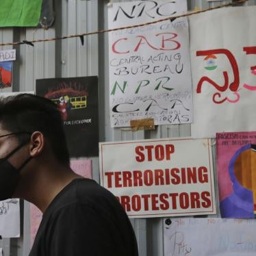 A man in a face mask stands in front of a variety of protest placards