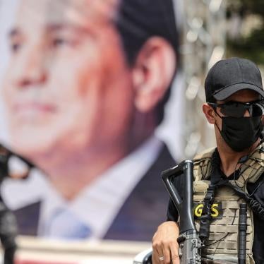 An Egyptian intelligence security detail member stands guard near a banner showing President Abdel Fattah al-Sisi.
