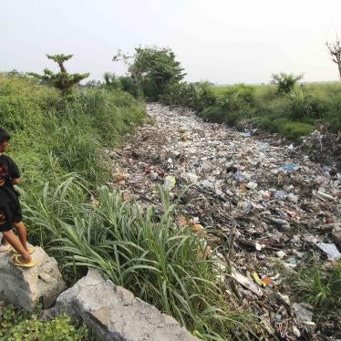 Two children stand above a river filled with garbage 