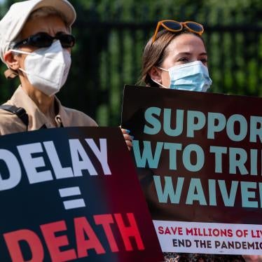 Protesters hold signs reading "Delay = Death" and "Support WTO Trips Waiver" during a demonstration ahead of the visit of German Chancellor Angela Merkel near the White House in Washington, DC, on July 15, 2021.