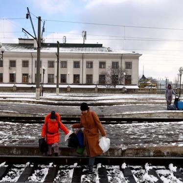 People fleeing Russia's invasion of Ukraine, cross train tracks to get to a train leaving for Poland, at the train station in Lviv