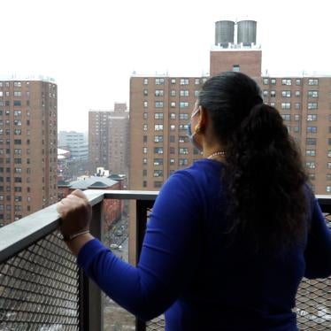 Woman standing on balcony looking at public housing buildings.