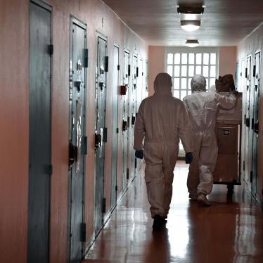 Two people in PPE walk down a prison corridor
