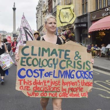 A protester holds a placard linking the climate crisis with the cost of living crisis