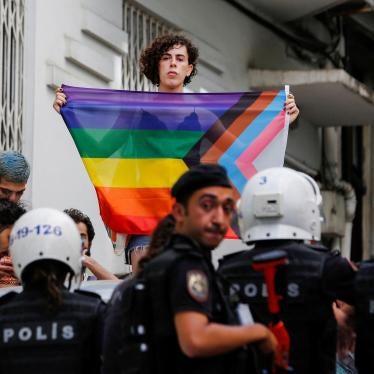 A demonstrator holds a rainbow flag in front of police officers as people try to gather for a Pride parade, which was banned by local authorities, in central Istanbul, Turkey June 26, 2022. REUTERS/Dilara Senkaya