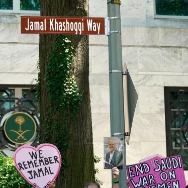 People hold placards in front of a new street sign reading Jamal Khashoggi Way