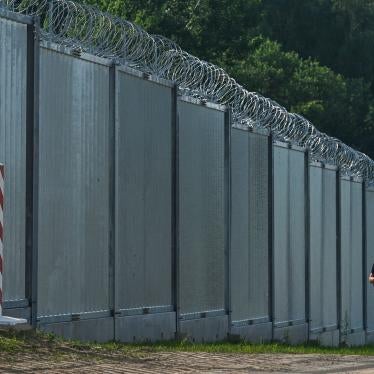 Polish border guards patrol along a fence