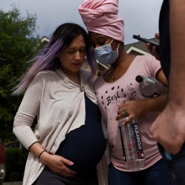 A pregnant woman holds onto another woman