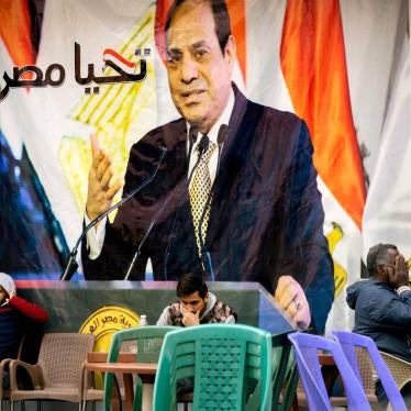 People sit under a banner with a picture of Egyptian President Abdel Fattah al-Sisi that reads, "Long live Egypt"