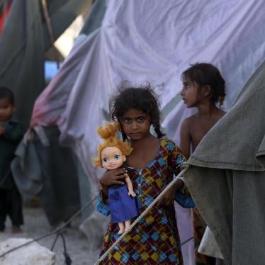 Children stand outside tents