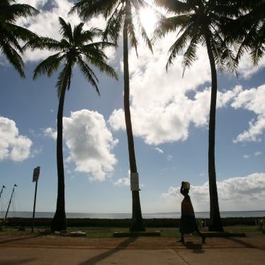 A woman walks past palm trees on Saibai Island in the Torres Strait