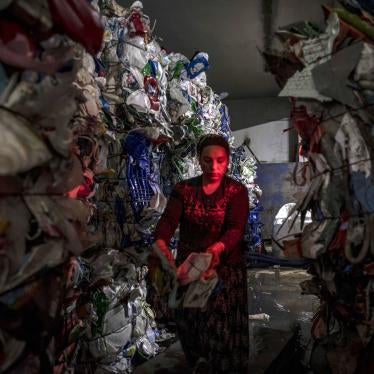 A woman stands between piles of plastic