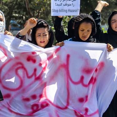 Women in hijabs march with protest signs