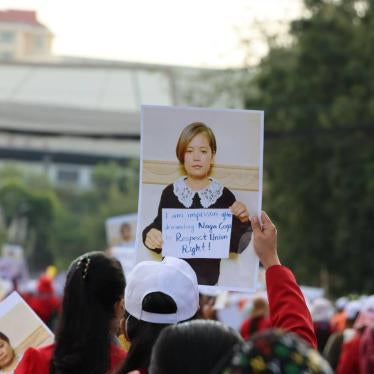 A crowd at a protest holds up a sign of a photo of a women 