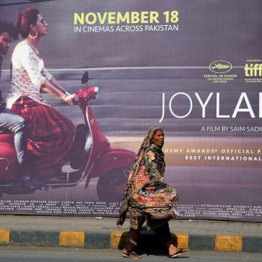 A woman walks past a promotional board for the film "Joyland" in Lahore, Pakistan