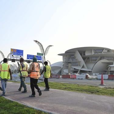 Construction workers walking by the National Museum of Qatar. 