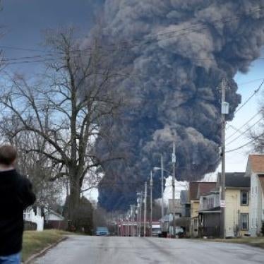 A man takes photos as a black plume rises over East Palestine, Ohio, as a result of a controlled detonation of a portion of the derailed Norfolk Southern trains, February 6, 2023.