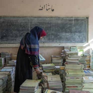 An Afghan teacher collects books in a school in Kabul, Afghanistan.