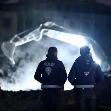Two police officers watch removal of rubble from buildings that collapsed in the February 6 earthquakes, Hatay, Turkey, March 23, 2023.