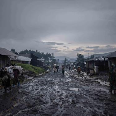 Après la pluie, des commerçants quittent le marché avec leurs sacs à Kitchanga