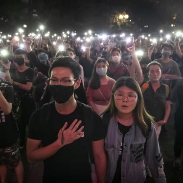 Photo of a crowd singing at a rally taken at night 