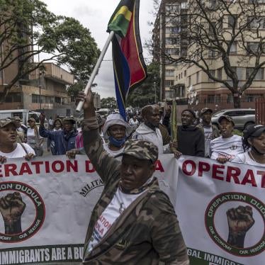 A man holds up a South African flag as members of "Operation Dudula" march down a street in the Hillbrow neighborhood to deliver memoranda to several businesses in the area, Johannesburg, South Africa, February 19, 2022. 
