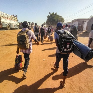 People displaced by conflict walk with their belongings in Wad Madani, the capital of al-Jazirah state, Sudan, December 16, 2023.