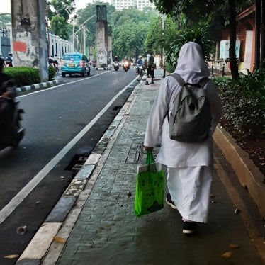 A schoolgirl walking near her state high school in Senayan, Jakarta, Indonesia. The mandatory school uniform includes a hijab, a long-sleeve shirt, and a long skirt.